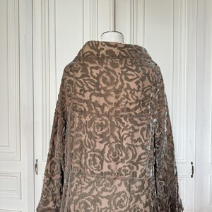 Puede incluir: Un abrigo largo marr&oacute;n con un dise&ntilde;o floral, exhibido en un maniqu&iacute;. Las mangas son largas, con pu&ntilde;os blancos. El abrigo tiene un cuello grande y cierre de botones. La tela parece ser terciopelo.