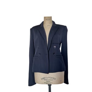 May include: A dark blue blazer with a double-breasted closure and long sleeves. The blazer has a classic tailored fit and features a small pocket on the left chest.