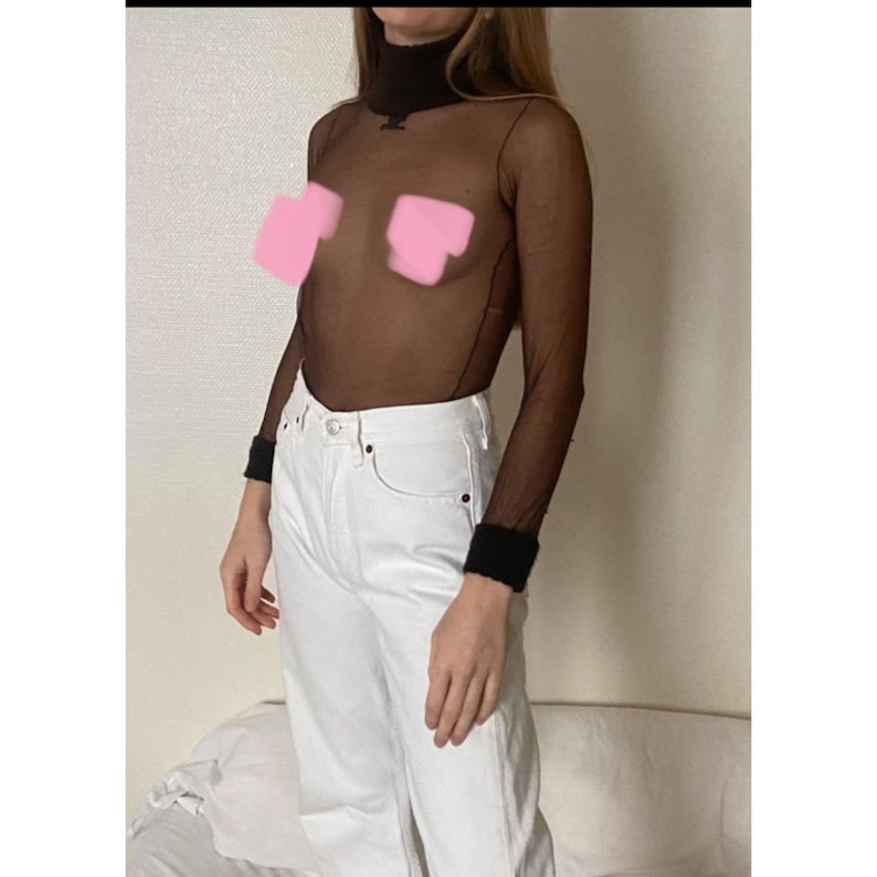 Op de afbeelding: Een zwart doorschijnend turtleneck-top met lange mouwen en een zwarte afwerking aan de manchetten. De top wordt gedragen over een witte jeans.