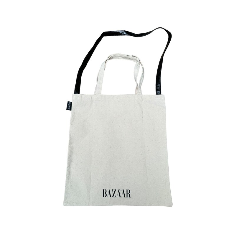 May include: A white canvas tote bag with black straps and the word "BAZAAR" printed on the front.