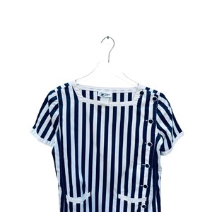 May include: A black and white striped short-sleeved dress with a button detail on the side. The dress has a scoop neck and a relaxed fit.