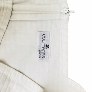 May include: White garment with a zipper and a white label that reads "Courr&egrave;ges Paris"