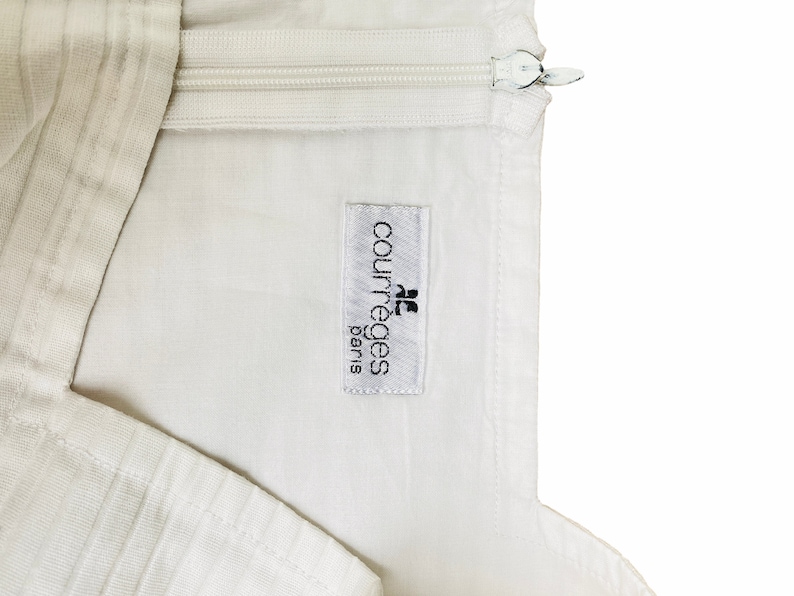 May include: White garment with a zipper and a white label that reads "Courr&egrave;ges Paris"