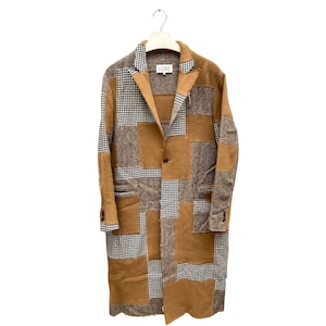 Op de afbeelding: Een lange bruine patchworkjas met een geruit patroon. De jas heeft een enkele knoopsluiting en twee zakken.