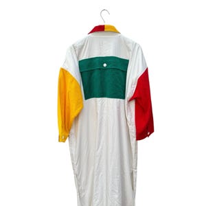 Puede incluir: Una camisa blanca de manga larga con un dise&ntilde;o de bloques de color verde, amarillo y rojo. La camisa tiene un cuello abotonado y un bolsillo de parche en la espalda.