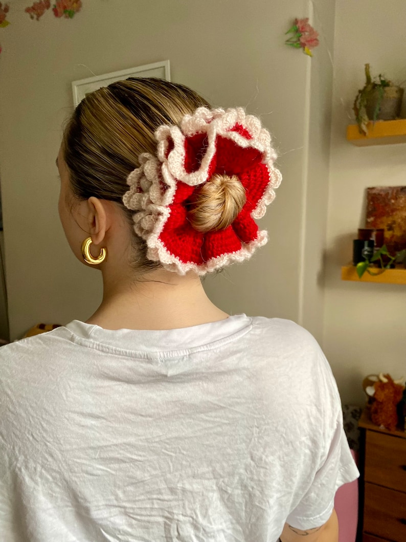 May include: A red and white crocheted hair scrunchie with a ruffled design.