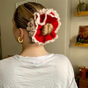 May include: A red and white crocheted hair scrunchie with a ruffled design.