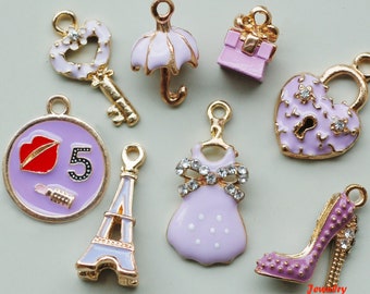 May include: Assortment of 10 purple and gold charm pendants, including a key, an umbrella, a gift box, a padlock, a dress, a Eiffel Tower, a high heel shoe, and a charm with a red lip and the number 5.