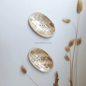 Puede incluir: Dos jaboneras ovaladas blancas con un dise&ntilde;o de mosaico dorado y blanco. Las jaboneras tienen agujeros de drenaje.
