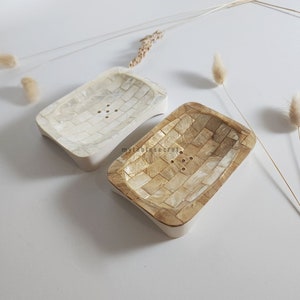 Puede incluir: Dos jaboneras rectangulares hechas de materiales naturales. Una es blanca y la otra es de color marr&oacute;n claro. Ambas tienen un patr&oacute;n tejido y agujeros de drenaje.
