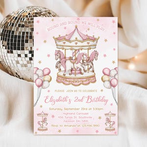 May include: A rectangular birthday invitation card featuring a pink and white carousel with horses, gold stars, and balloon clusters. The text reads: ROUND AND ROUND WE WILL PLAY, PLEASE JOIN US TO CELEBRATE, Elizabeth's 2nd Birthday, Saturday, September 23rd at 5:30pm, Highland Carousel, 456 Tunas St. Southville, Jackson DA, 5891, RSVP to Amanda at 123.456.7890.