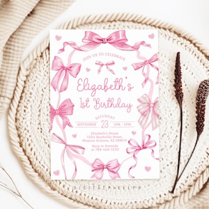 May include: A rectangular birthday invitation card featuring a white background with pink watercolor bows and ribbons framing the text. The card reads Elizabeth's 1st Birthday, Saturday, September 23, 1pm-5pm, Elizabeth's House, 1234 Southville Street, Phoenix Arizona, AZ 85008, Rsvp to Amanda at 788-456-1230.