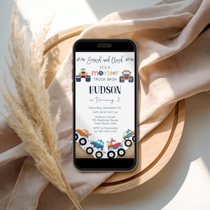 May include: A smartphone screen shows a digital invitation for a monster truck-themed birthday party. The invitation features illustrations of monster trucks and the text "Smash and Crash." It announces Hudson's second birthday, with event details including the date, time, and location.