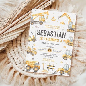 Puede incluir: Una invitación de cumpleaños con ilustraciones en acuarela de vehículos de construcción amarillos y grises. La invitación incluye el texto "¡Sebastián cumple 3 años!" y los detalles del evento. La invitación está sobre un fondo neutro.
