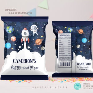 Puede incluir: Dos bolsas de patatas fritas azul marino con temática espacial. Un lado presenta un cohete, un astronauta, planetas y el texto "Cameron's first trip around the sun". El otro lado tiene información nutricional y "Thank you for coming to my party."