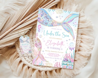 Könnte beinhalten: Eine rechteckige Einladungskarte und ein kleiner passender Anhänger mit Schnur, beide mit Illustrationen von einer Meerjungfrauenflosse, Meeresbewohnern und Korallen. Der Text lautet: Please join us Under the Sea, Elizabeth is turning 5, 23. September.