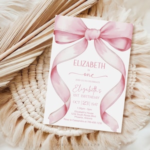 May include: A light pink birthday invitation card with a watercolor bow and ribbon design. The card reads "Elizabeth is one" and includes event details. The invitation is set against a neutral, textured background.