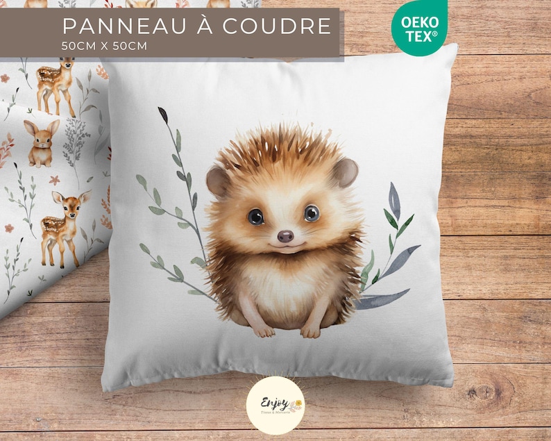 May include: A white pillowcase featuring a watercolour illustration of a hedgehog with brown fur and a light brown nose. The hedgehog is surrounded by green and blue leaves. The pillowcase is 50 cm x 50 cm and has the text "PANNEAU &Agrave; COUDRE" and "Oeko Tex&reg;" printed on it.
