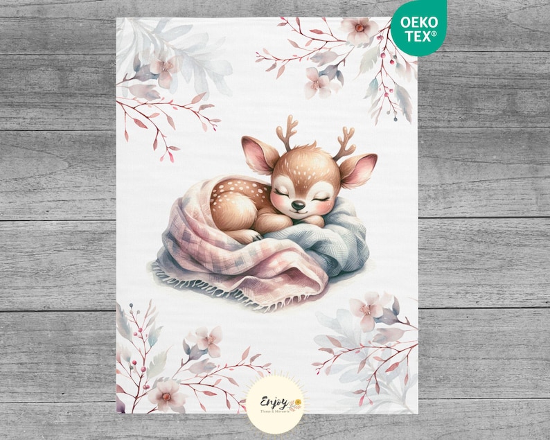 May include: A watercolor illustration of a fawn sleeping in a pink and blue blanket with white flowers and leaves in the background. The text "Enjoy" is at the bottom of the image.