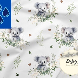 K&ouml;nnte beinhalten: Wei&szlig;er Stoff mit einem sich wiederholenden Muster aus Aquarell-Koala-B&auml;ren, umgeben von gr&uuml;nen Bl&auml;ttern und braunen Herzen. Der Text "Exclusive Enjoy Tissus & Mercerie" befindet sich in einem Kreis unten rechts im Bild.