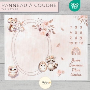 Può includere: Una coperta per bambini rosa e marrone con un cerchio al centro e una varietà di animali del bosco, tra cui uno scoiattolo, un coniglio, un gufo, un riccio e un procione. La coperta presenta anche un design floreale e i numeri da 1 a 12. Il testo "PANNEAU À COUDRE" e "TAPIS ÉTAPE" è in cima alla coperta. Il testo "OEKO TEX®" è nell'angolo in alto a destra. Il testo "Jours Semaines Mois Années" è nell'angolo in basso a destra. Il testo "Enjoy" è al centro in basso della coperta.