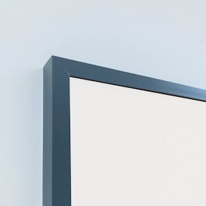 May include: A close-up of the top corner of a white dry erase board with a dark blue frame.
