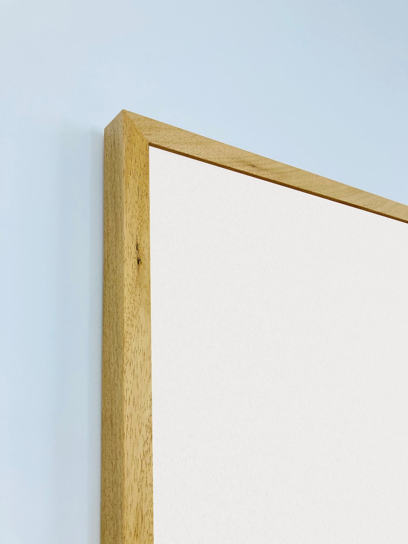 May include: Close-up of the top corner of a light wood picture frame. The frame is made of natural wood with a smooth finish. The frame is empty and ready to be filled with a picture or artwork.