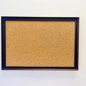 May include: A brown corkboard with a black frame.