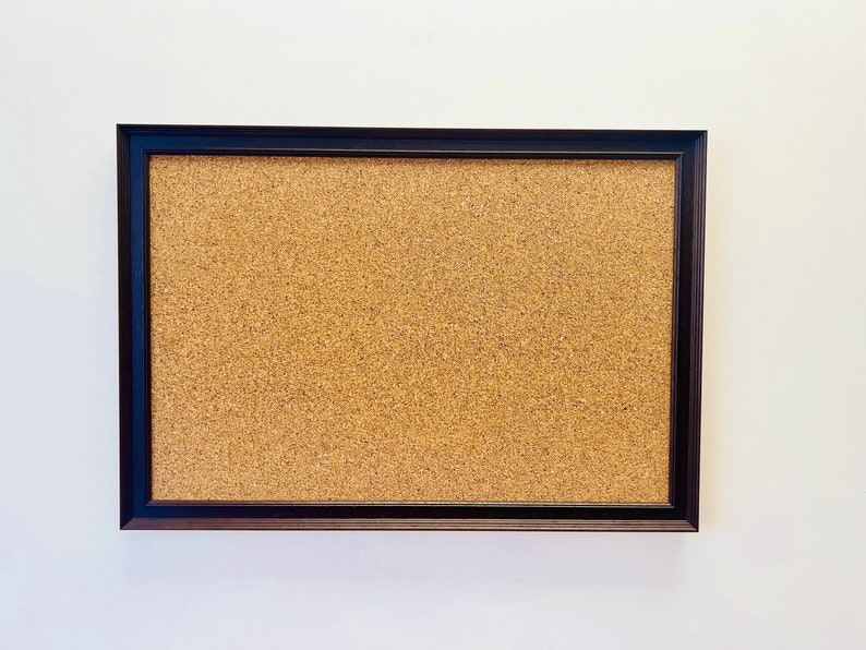 May include: A brown corkboard with a black frame.