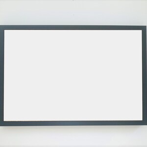 May include: A blank, white rectangular sign with a dark gray frame.