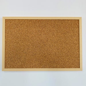 May include: A corkboard with a natural wood frame. The corkboard is brown and has a textured surface.