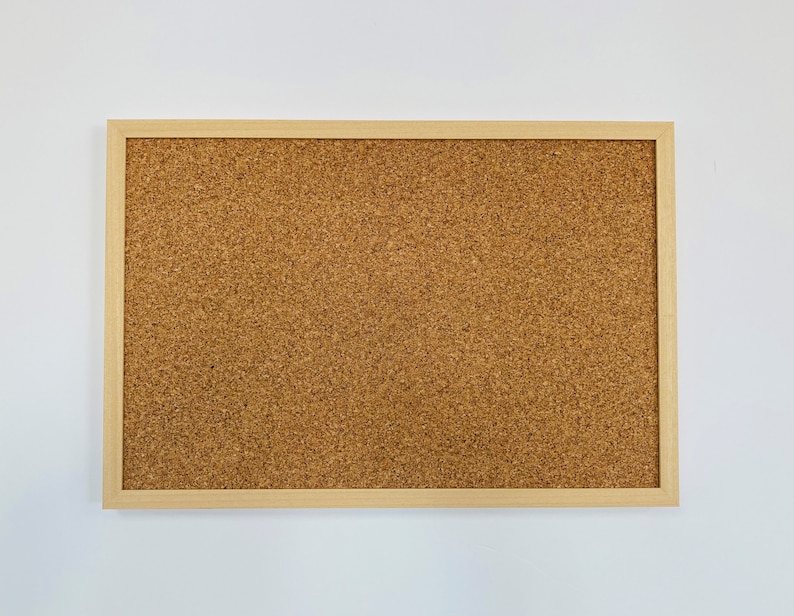 May include: A corkboard with a natural wood frame. The corkboard is brown and has a textured surface.