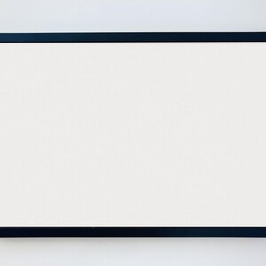 May include: A black picture frame with a white mat and a white background.