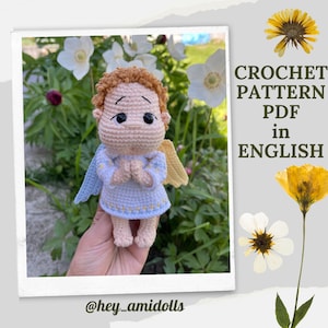 Könnte beinhalten: Häkelanleitung PDF in Englisch für eine gehäkelte Engelpuppe mit einem hellblauen Kleid, gelben Flügeln und braunen Haaren. Die Puppe hält ihre Hände zum Beten zusammen.