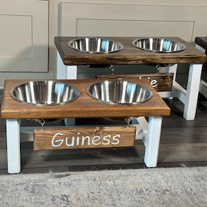 May include: A wooden dog bowl stand with two stainless steel bowls. The stand is painted white and has a sign that says "Guinness".