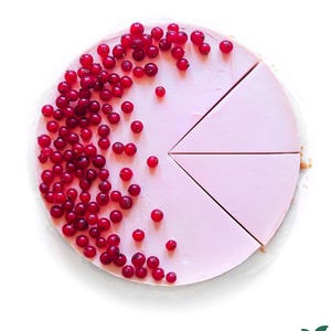 Può includere: Una torta rosa, parzialmente tagliata a fette, guarnita con ribes rossi freschi. La torta è su una superficie bianca, con alcuni ribes sparsi. Un dessert visivamente accattivante.
