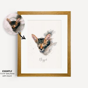 May include: A watercolor painting of a sleeping cat named "Nugget" in a brown wooden frame. The cat is brown and black with white markings. The painting is on a white background with a gray watercolor wash.
