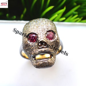 Op de afbeelding: Een zilveren schedelring met pavé-gezet diamanten en rode robijnogen.