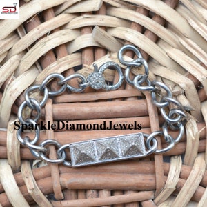 May include: A silver bracelet with a rectangular center piece featuring three pyramid-shaped designs. The bracelet has a chain link design and a clasp closure. The text "SparkleDiamondJewels" is visible on the image.