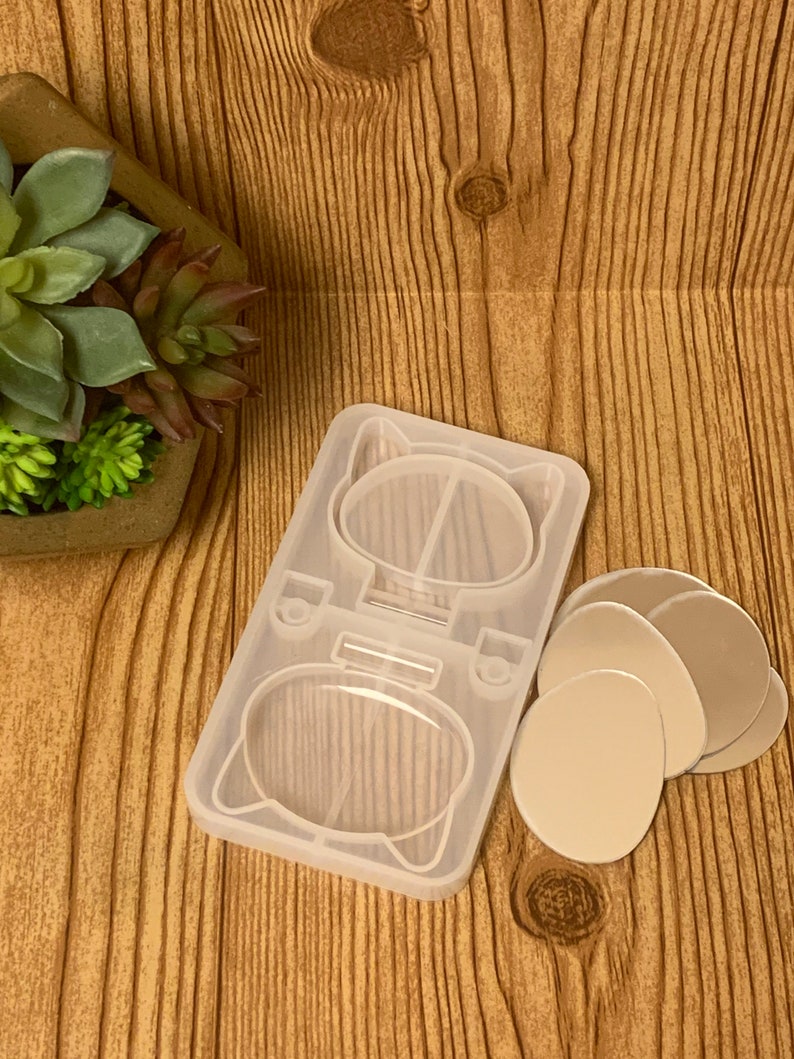 May include: A clear silicone mold for making resin crafts. The mold is shaped like a cat with two round cavities for making earrings or charms. The mold comes with four clear round silicone molds for making additional charms.