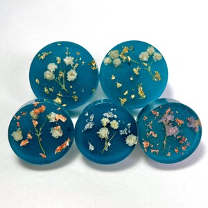 Pomos y tiradores redondos para muebles en turquesa y verde azulado con botones con copos de metal y flores secas en estilo bohemio.