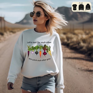 Könnte beinhalten: Weißer Pullover mit einem Aufdruck einer Reihe bunter Gemüse und dem Text "Let's root for each other and watch each other grow".