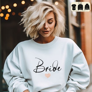 Puede incluir: Sudadera blanca con la palabra "Bride" en letra negra y un pequeño corazón rosa.