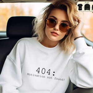 May include: White sweatshirt with the text "404: Motivation not found!" printed in black.