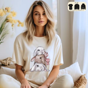 a woman sitting on a bed wearing a t - shirt with a picture of a