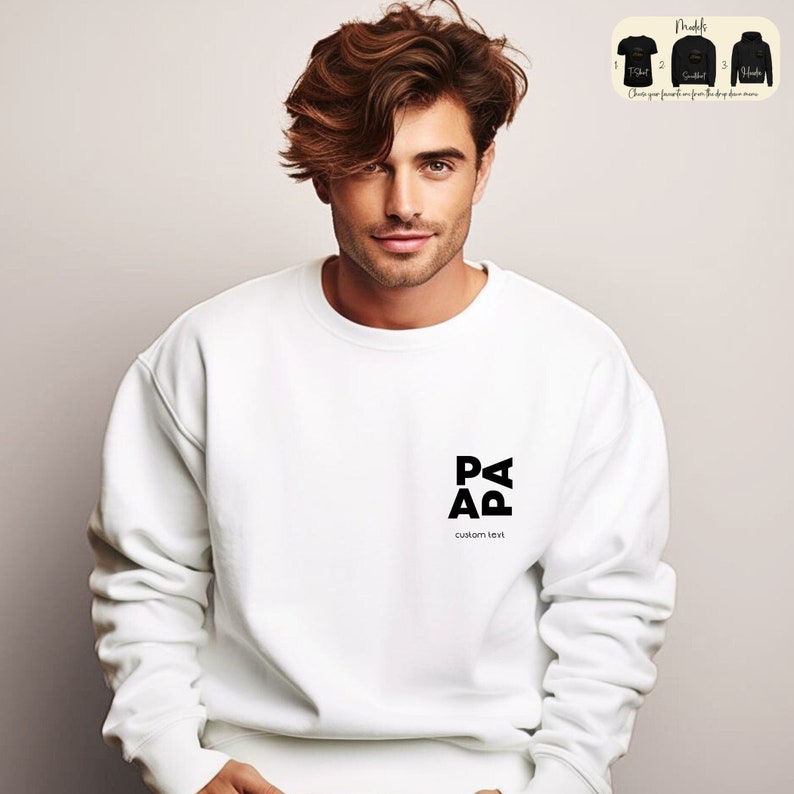 Op de afbeelding: Witte trui met een zwart logo dat "PAPA" zegt met de tekst "custom text" eronder.