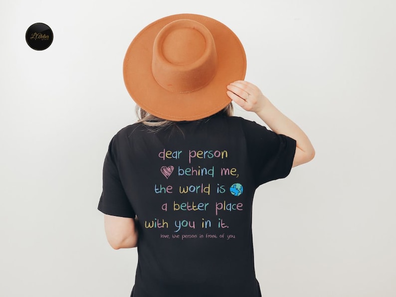 May include: Black t-shirt with a colorful graphic that reads "dear person behind me, the world is a better place with you in it. love the person in front of you".