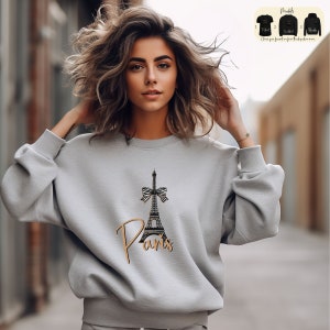 a woman wearing a sweatshirt with the eiffel tower on it