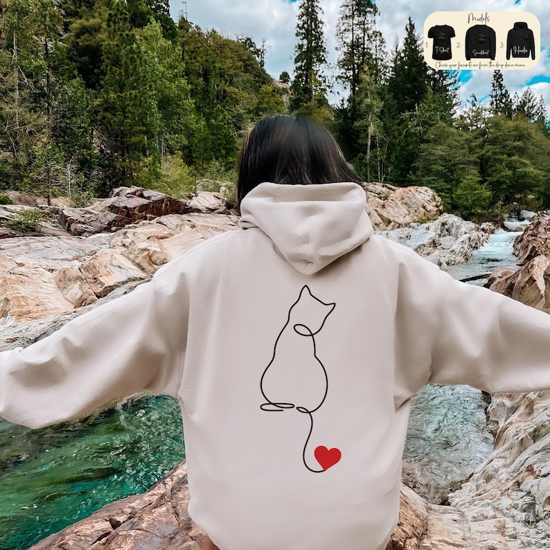 a woman wearing a white hoodie with a picture of a cat on it