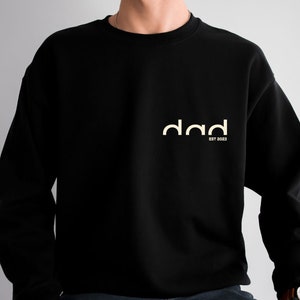May include: Black sweatshirt with a white graphic that says "dad est 2023".